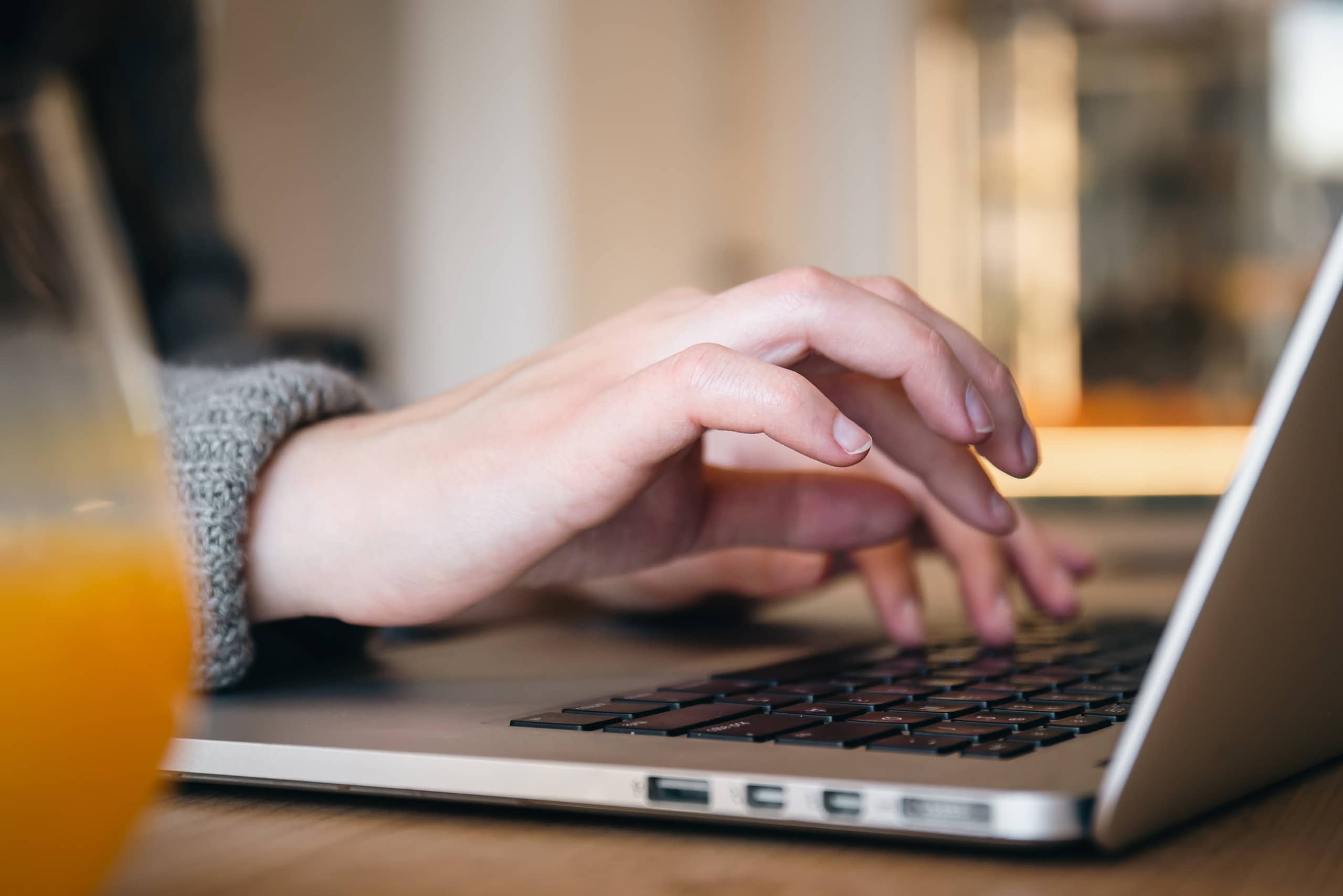 Close-up, female hands are typing on a laptop.