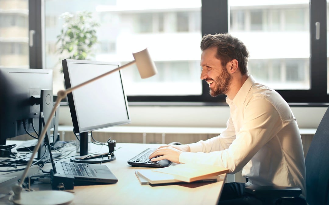 An young professional smiling after reading something in his desktop screen Business email etiquette