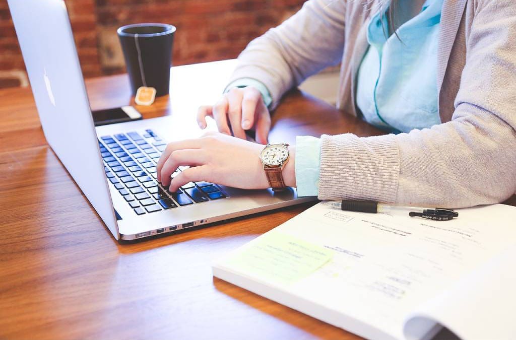 A lady working on his laptop with a book besides her More about email signature